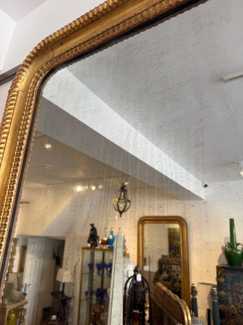 A tall rectangular antique French wall mirror featuring a gold gilded frame with rounded upper corners and textured ripple moulding. View VII