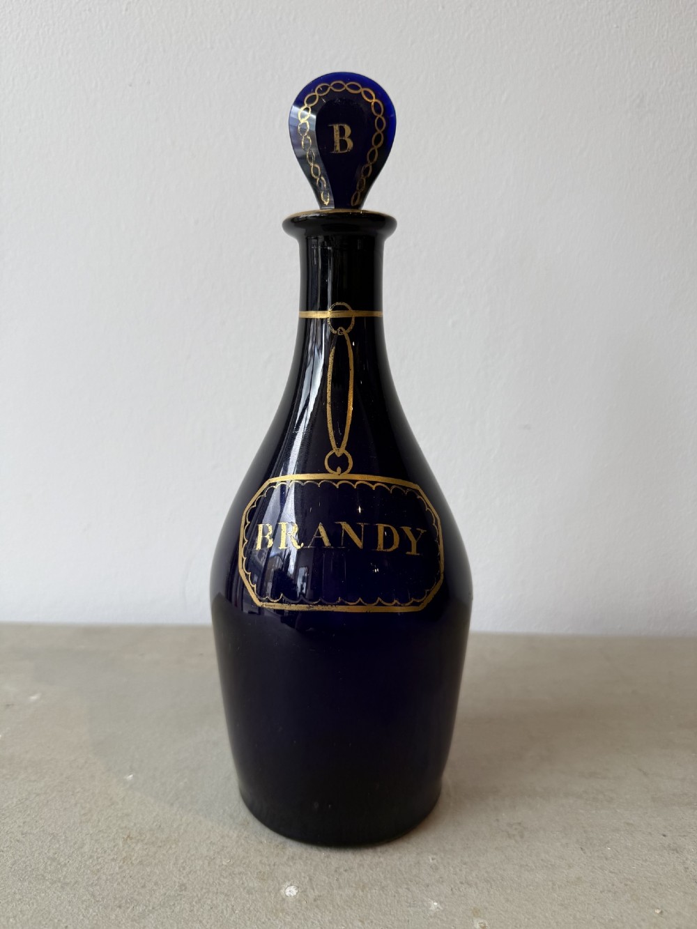 A set of three cobalt blue glass decanters with gilded labels for Brandy, Hollands, and Rum, complete with matching initialled stoppers. View III