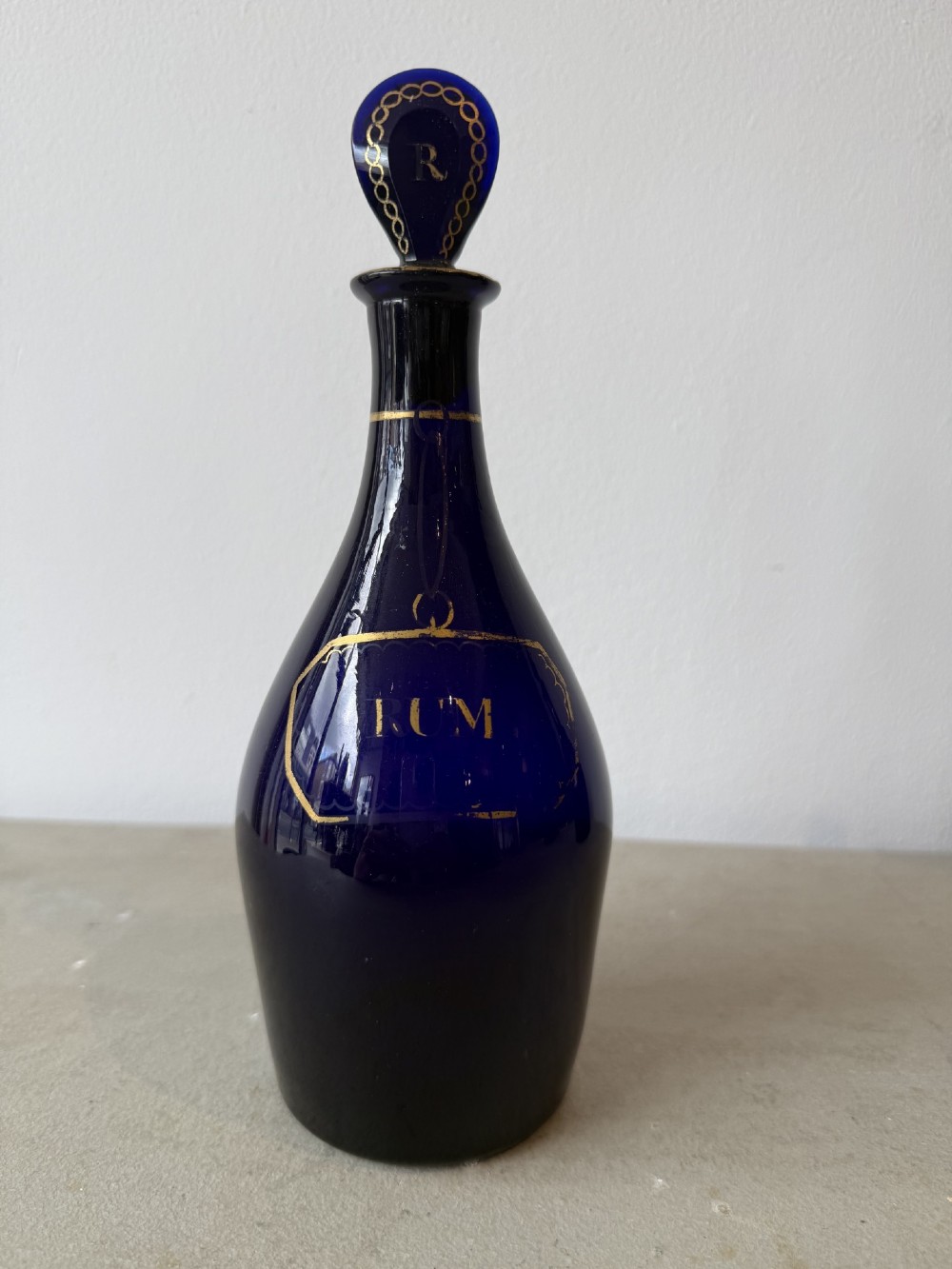 A set of three cobalt blue glass decanters with gilded labels for Brandy, Hollands, and Rum, complete with matching initialled stoppers. View IV