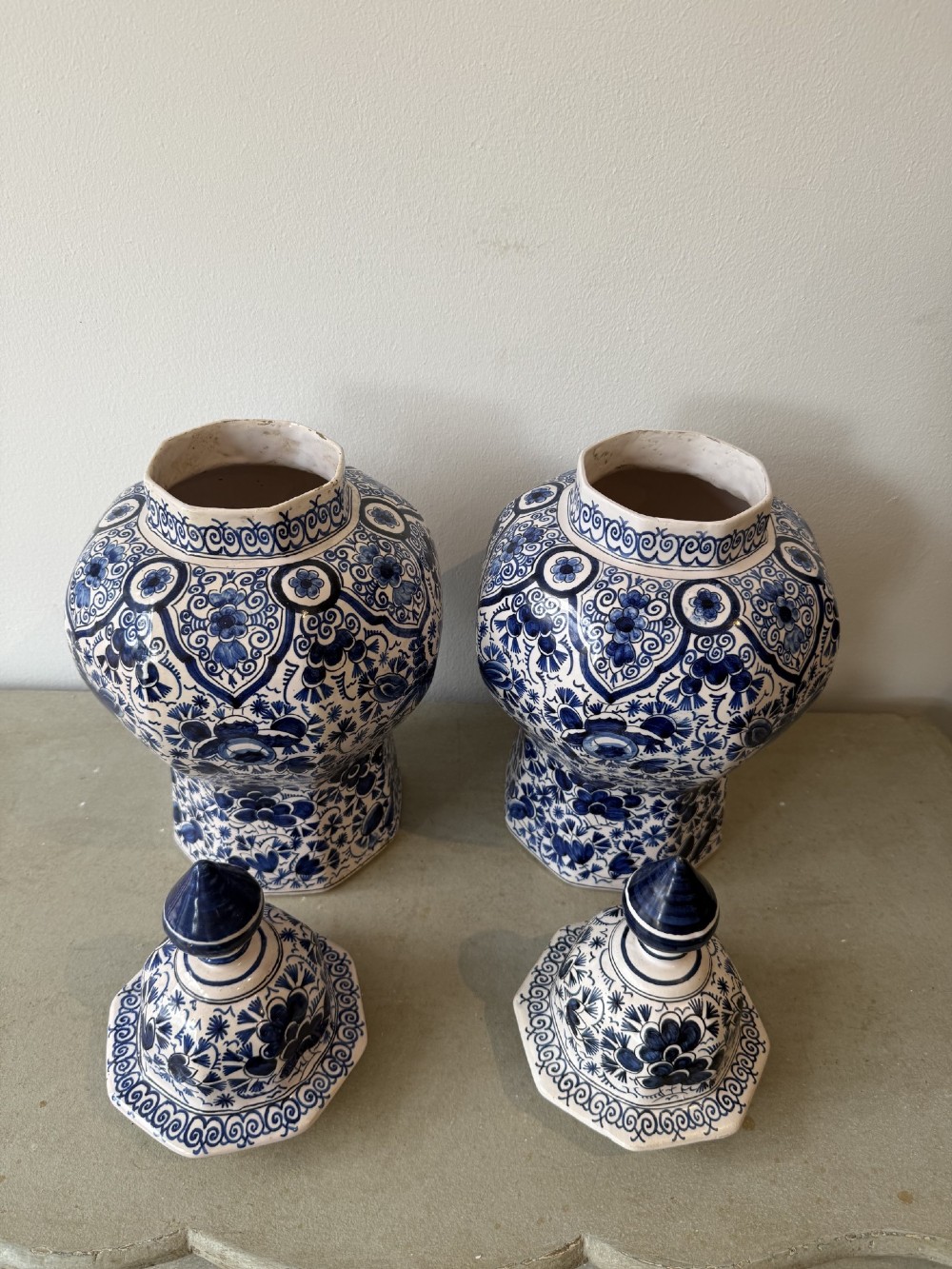 A pair of octagonal tin-glazed earthenware lidded vases decorated with hand-painted blue floral patterns on a white ground, topped with pointed finials. View III