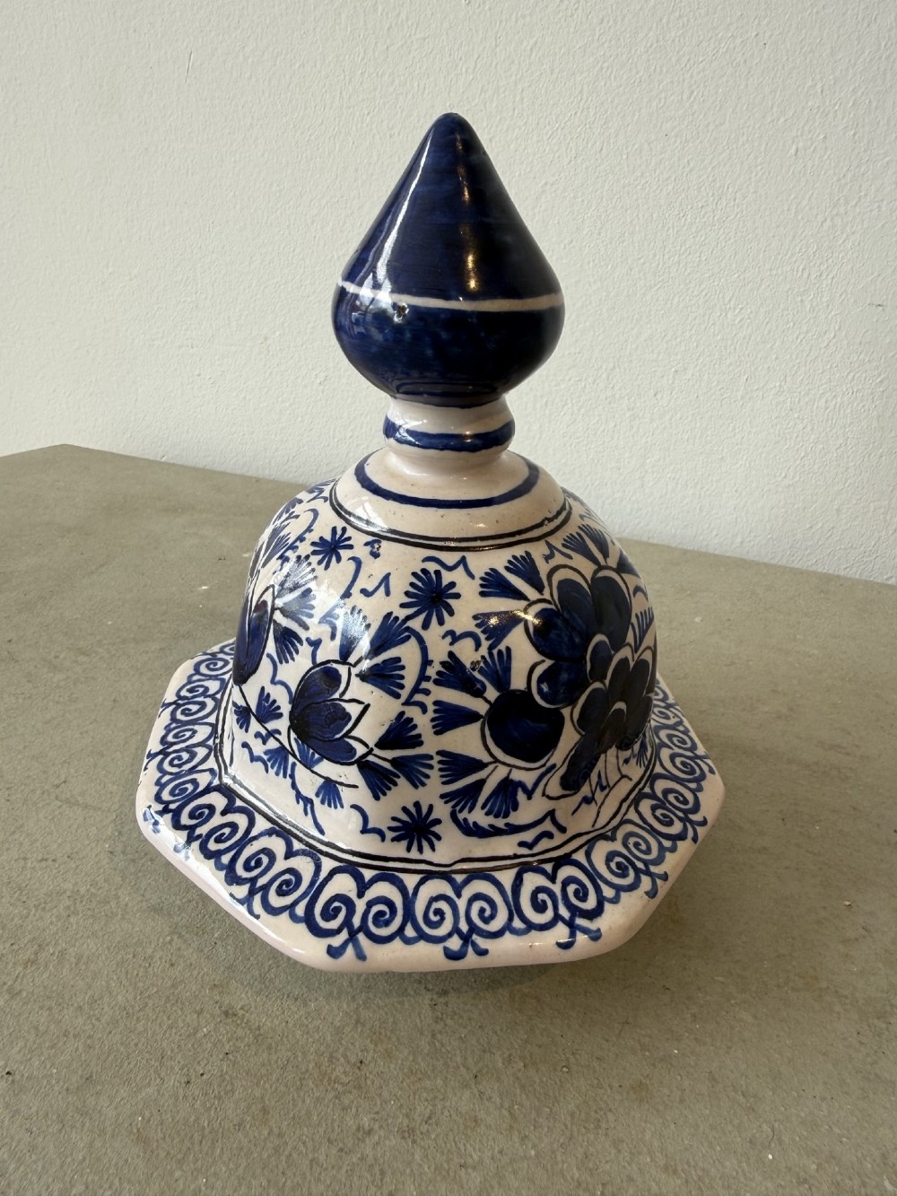 A pair of octagonal tin-glazed earthenware lidded vases decorated with hand-painted blue floral patterns on a white ground, topped with pointed finials. View V
