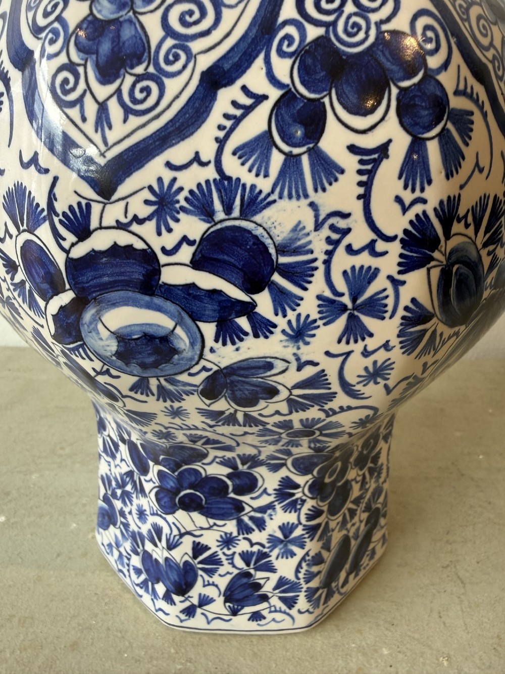 A pair of octagonal tin-glazed earthenware lidded vases decorated with hand-painted blue floral patterns on a white ground, topped with pointed finials. View VI