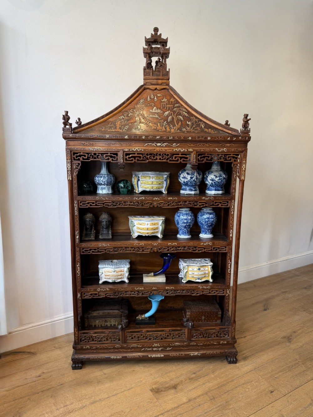 A tall dark wood Chinese pagoda display cabinet featuring mother of pearl inlay, carved fretwork, and four open shelves.