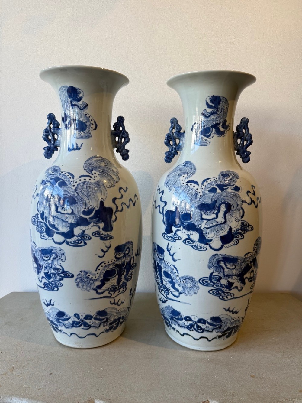 A pair of large Chinese porcelain baluster vases painted in cobalt blue underglaze with guardian lion motifs and decorative scrolled handles.