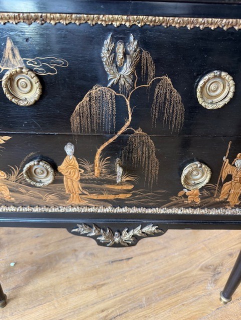 A pair of black lacquered Louis XVI style commodes featuring gold gilt Chinoiserie landscapes, marble tops, and tapered fluted legs. View X