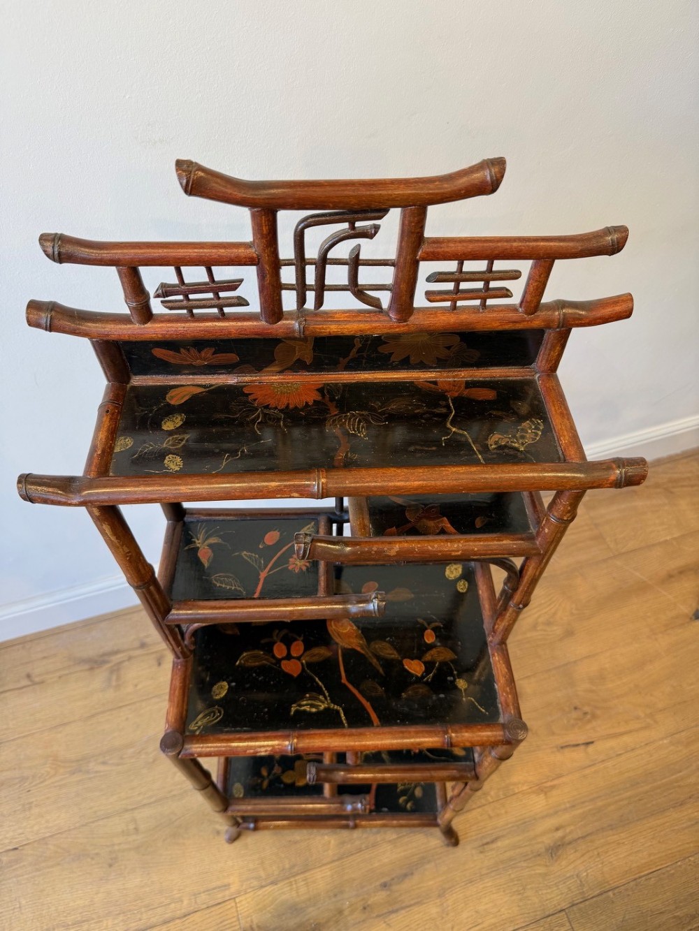 A dark bamboo tiered etagere display shelf with a pagoda-shaped top and black lacquer shelves painted with floral motifs. View IV