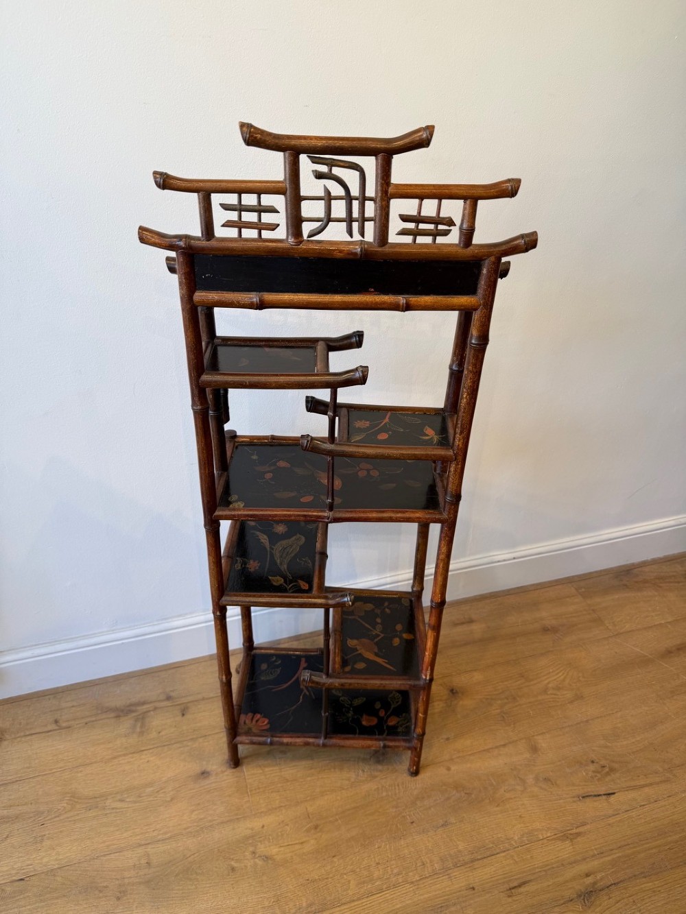 A dark bamboo tiered etagere display shelf with a pagoda-shaped top and black lacquer shelves painted with floral motifs. View V