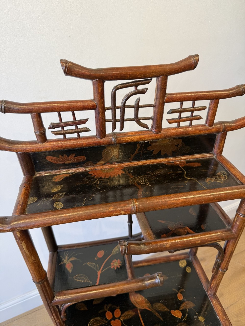 A dark bamboo tiered etagere display shelf with a pagoda-shaped top and black lacquer shelves painted with floral motifs. View VIII