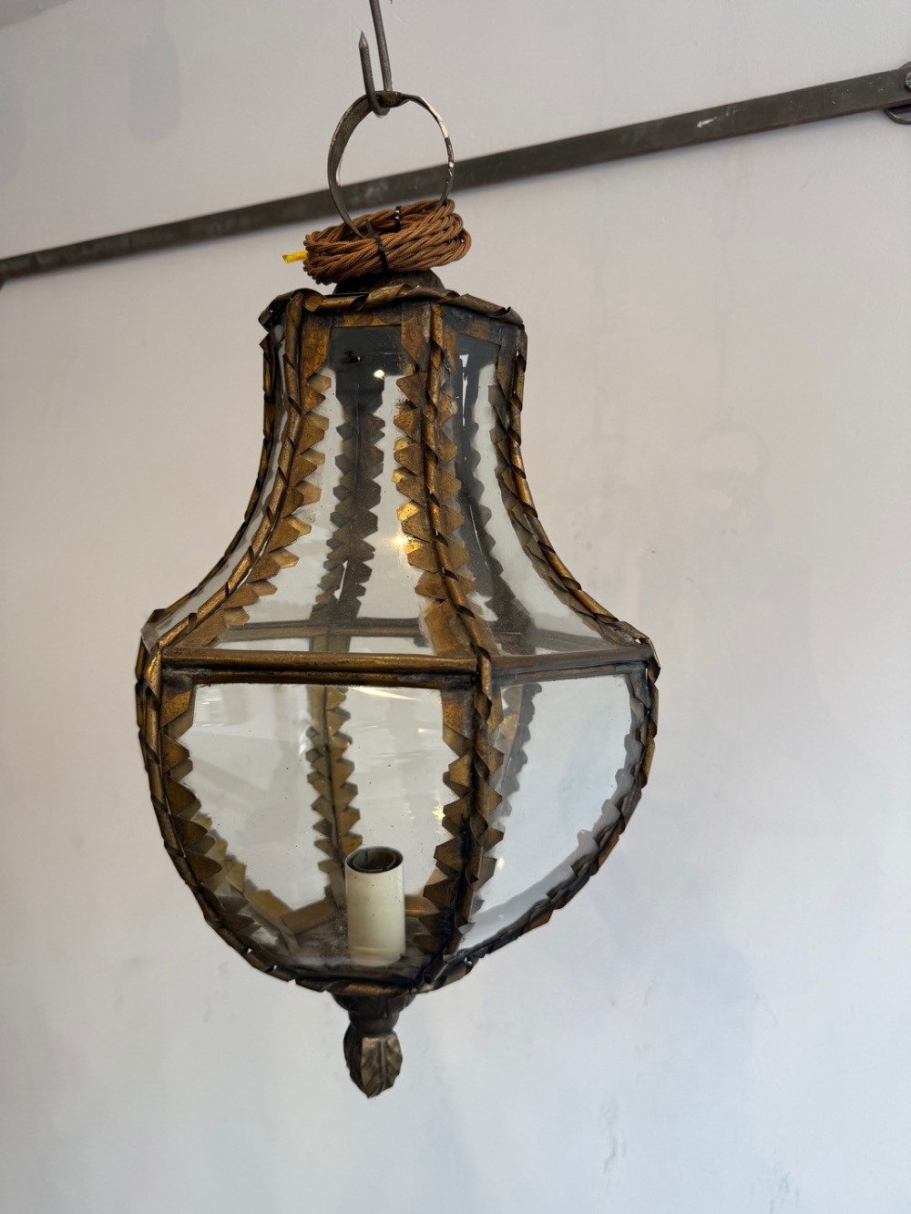 A vintage brass pendant lantern featuring curved glass panels framed with notched brass edging and a decorative bottom finial. View III