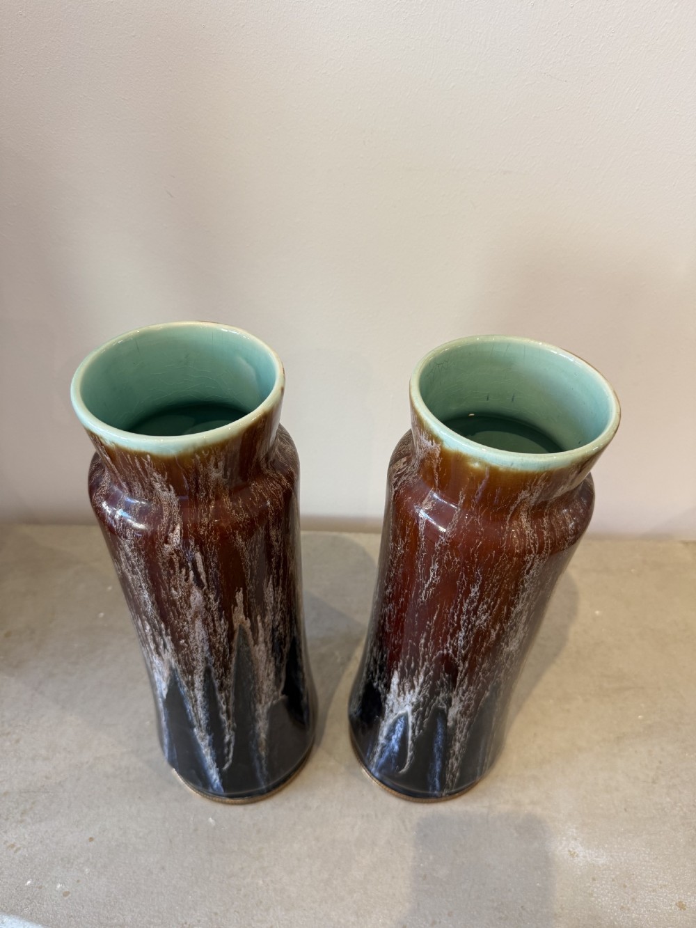 A pair of tall cylindrical antique ceramic vases featuring a dark brown and black drip glaze finish with brass mounts at the base. View II