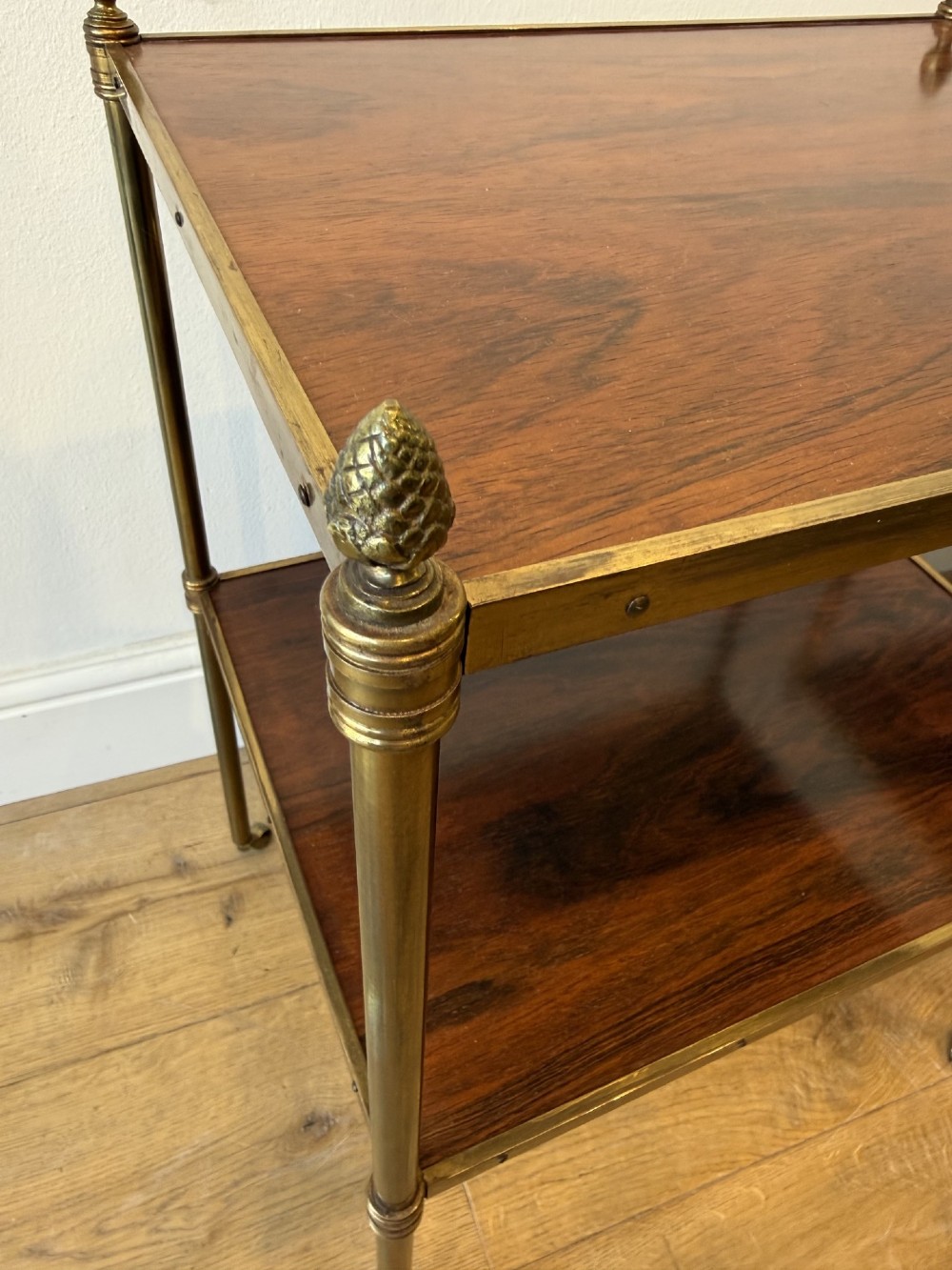 A pair of two-tier brass side tables featuring dark polished wood shelves, finial tops, and slender legs with small castors. View IX
