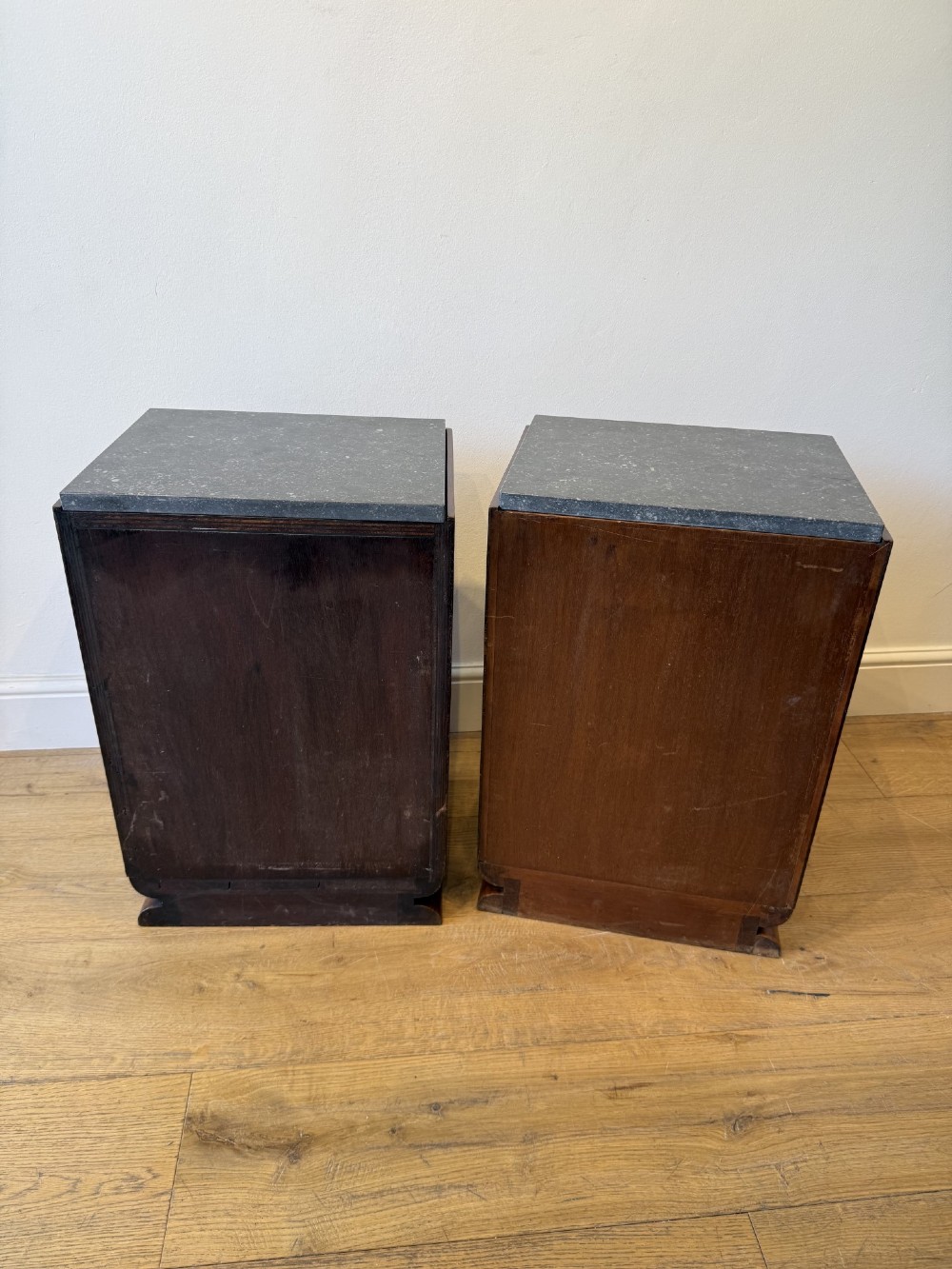 A pair of Art Deco burr walnut bedside cabinets featuring dark stone tops, open upper shelves, and single cupboard doors with square metal handles. View VII