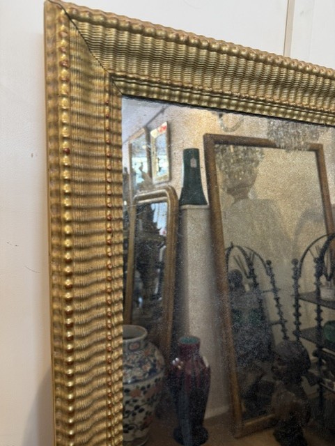 A large rectangular 19th-century wall mirror featuring a textured gold ripple-moulded frame. View III