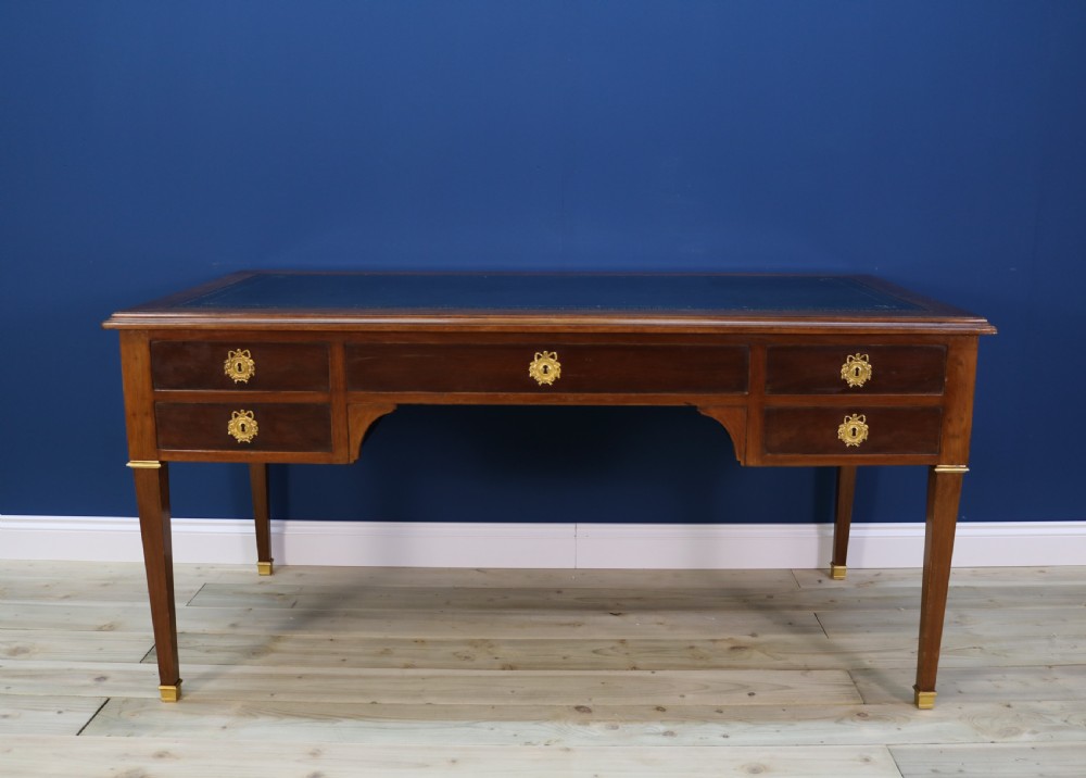 A nineteenth-century Directoire-style wooden bureau plat desk featuring five drawers with brass keyhole escutcheons, tapered legs with brass feet, and a dark leather inset writing top. View III