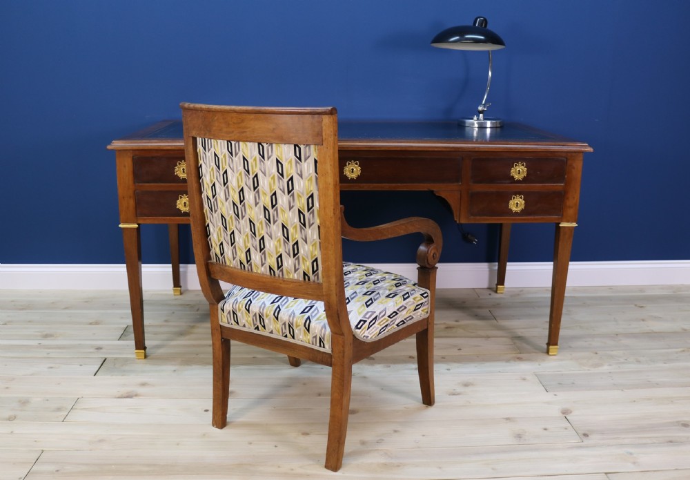 A nineteenth-century Directoire-style wooden bureau plat desk featuring five drawers with brass keyhole escutcheons, tapered legs with brass feet, and a dark leather inset writing top. View V