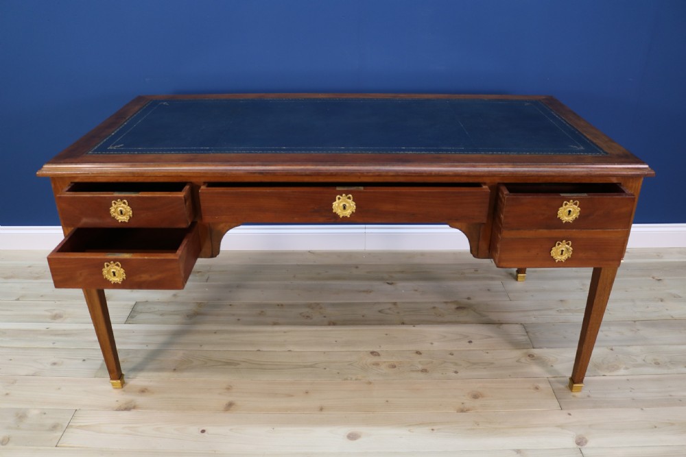 A nineteenth-century Directoire-style wooden bureau plat desk featuring five drawers with brass keyhole escutcheons, tapered legs with brass feet, and a dark leather inset writing top. View VIII