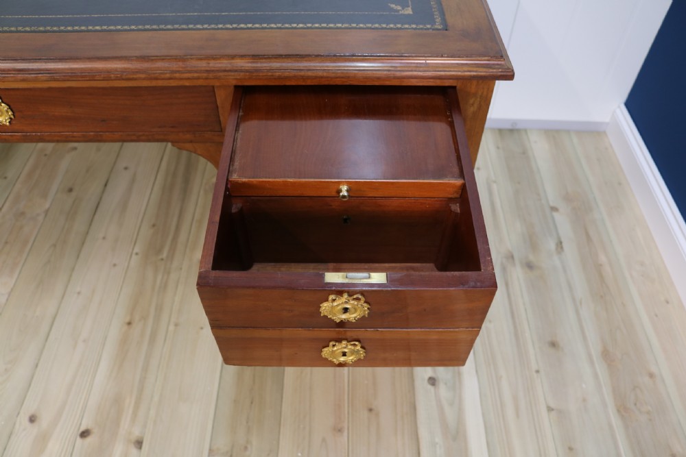 A nineteenth-century Directoire-style wooden bureau plat desk featuring five drawers with brass keyhole escutcheons, tapered legs with brass feet, and a dark leather inset writing top. View XI
