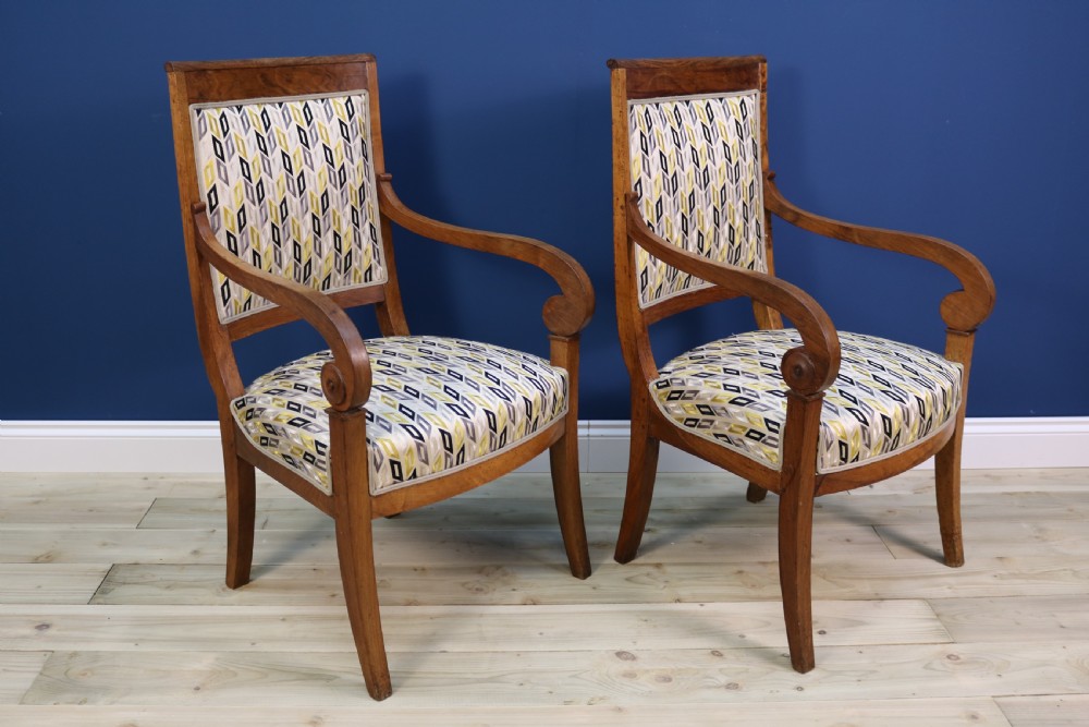 A pair of nineteenth-century French walnut fauteuils featuring scrolled armrests, raked backs, and patterned geometric upholstery.