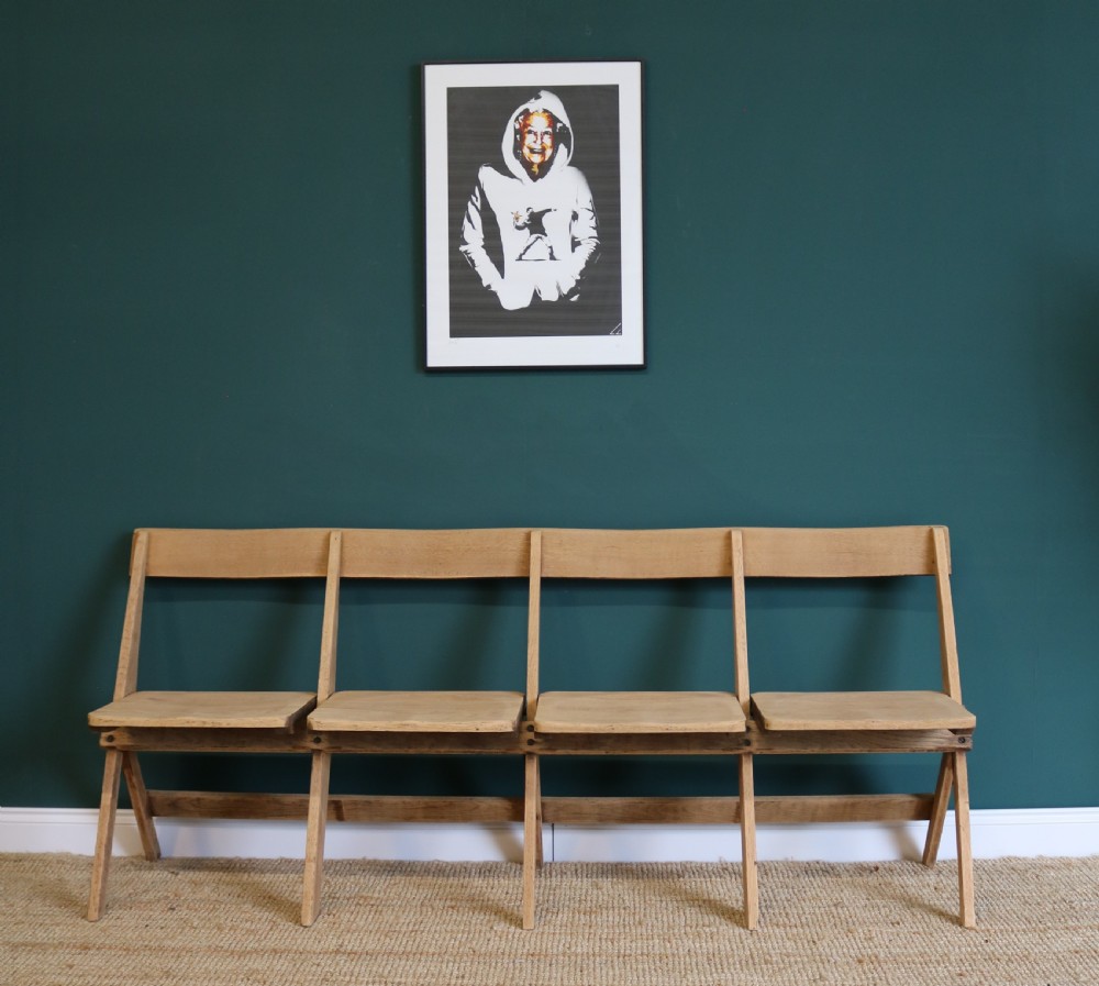 A four-seat antique folding oak bench with integrated iron hinges and sloped backrests positioned on a woven rug. View III