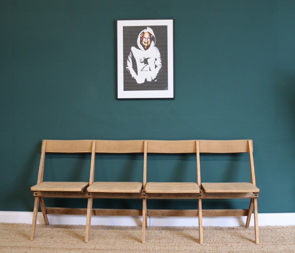 A four-seat antique folding oak bench with integrated iron hinges and sloped backrests positioned on a woven rug. View II