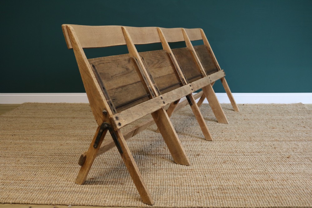 A four-seat antique folding oak bench with integrated iron hinges and sloped backrests positioned on a woven rug. View IV