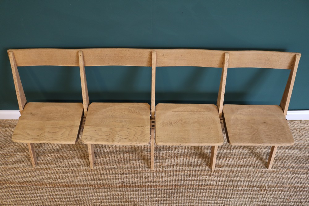 A four-seat antique folding oak bench with integrated iron hinges and sloped backrests positioned on a woven rug. View VIII