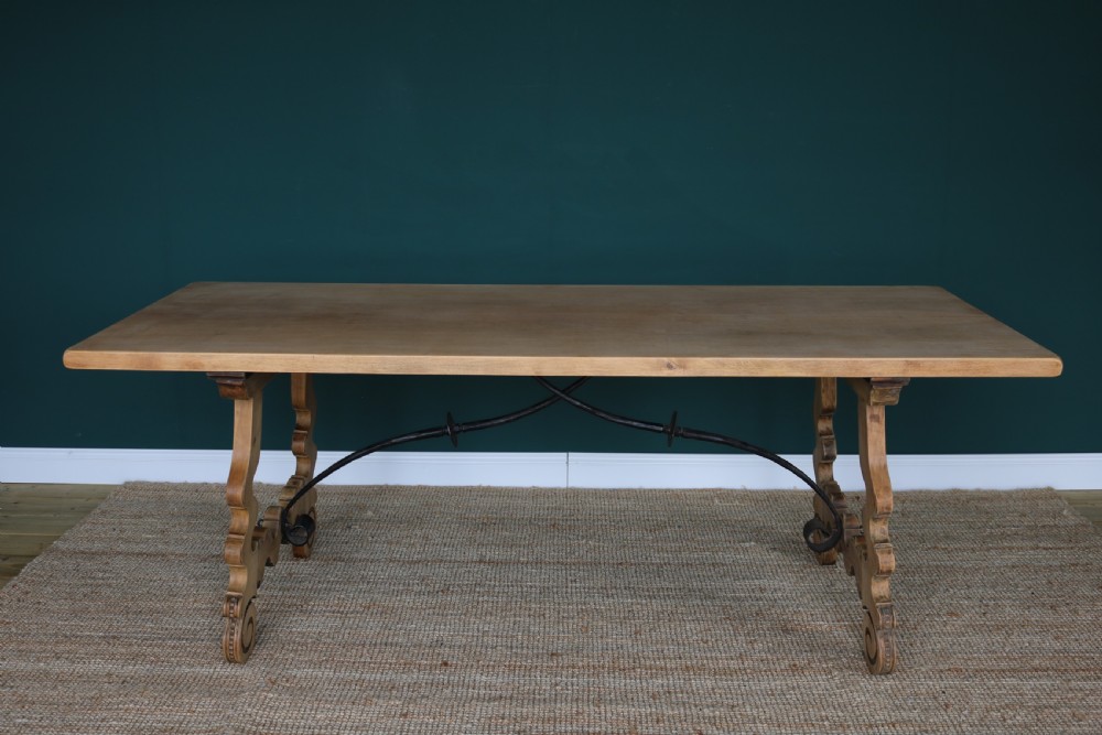 A solid walnut dining table featuring a rectangular plank top, scrolled lyre-shaped trestle legs, and curved wrought iron stretchers. View II