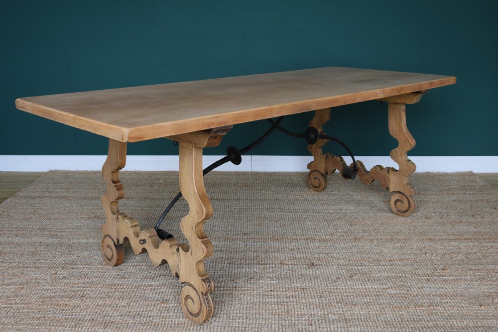 A solid walnut dining table featuring a rectangular plank top, scrolled lyre-shaped trestle legs, and curved wrought iron stretchers. View III