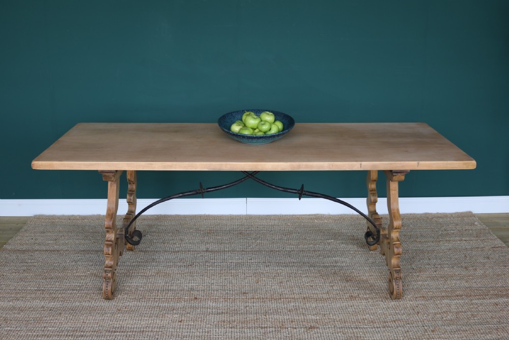 A solid walnut dining table featuring a rectangular plank top, scrolled lyre-shaped trestle legs, and curved wrought iron stretchers. View IX