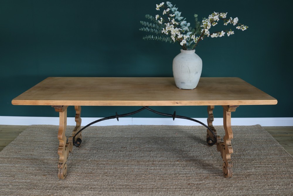A solid walnut dining table featuring a rectangular plank top, scrolled lyre-shaped trestle legs, and curved wrought iron stretchers. View XIV