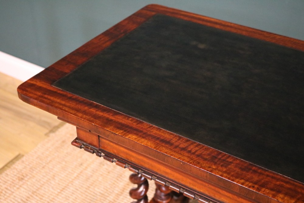 A William IV Goncalo Alves writing table featuring a dark green leather inset top, twin barley twist leg supports, and a central turned stretcher. View VI