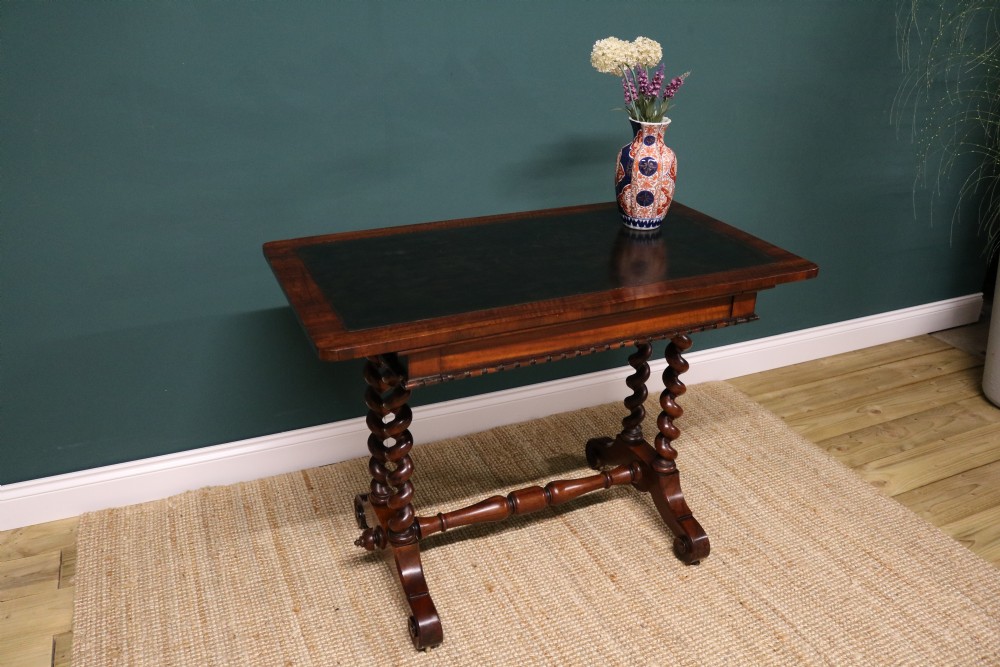 A William IV Goncalo Alves writing table featuring a dark green leather inset top, twin barley twist leg supports, and a central turned stretcher. View X