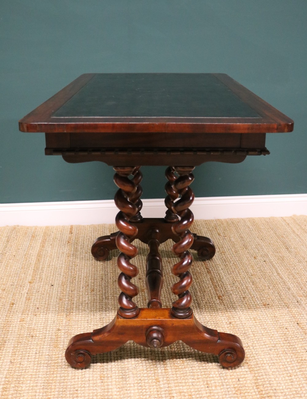 A William IV Goncalo Alves writing table featuring a dark green leather inset top, twin barley twist leg supports, and a central turned stretcher. View XIX