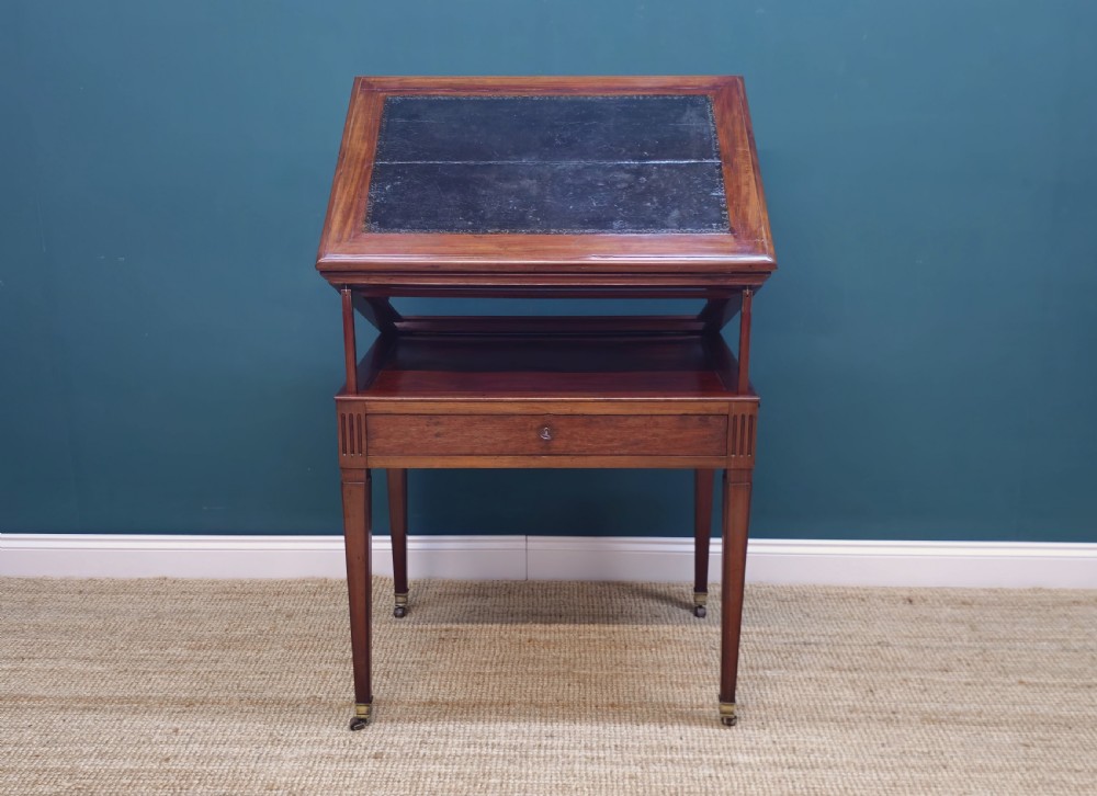 A nineteenth-century French mahogany architects desk featuring a leather inset top, single apron drawer, fluted corners, and tapered legs on brass castors. View IV