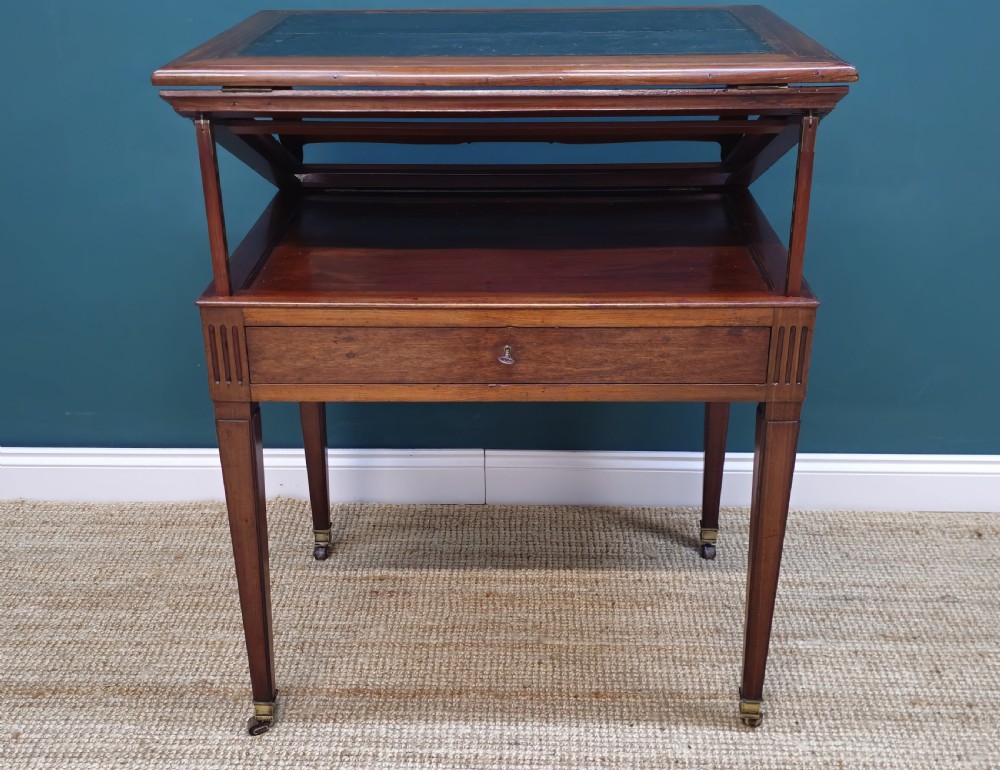 A nineteenth-century French mahogany architects desk featuring a leather inset top, single apron drawer, fluted corners, and tapered legs on brass castors. View V