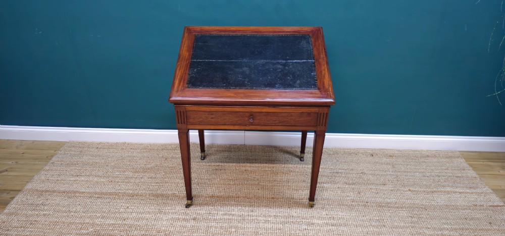 A nineteenth-century French mahogany architects desk featuring a leather inset top, single apron drawer, fluted corners, and tapered legs on brass castors. View VI