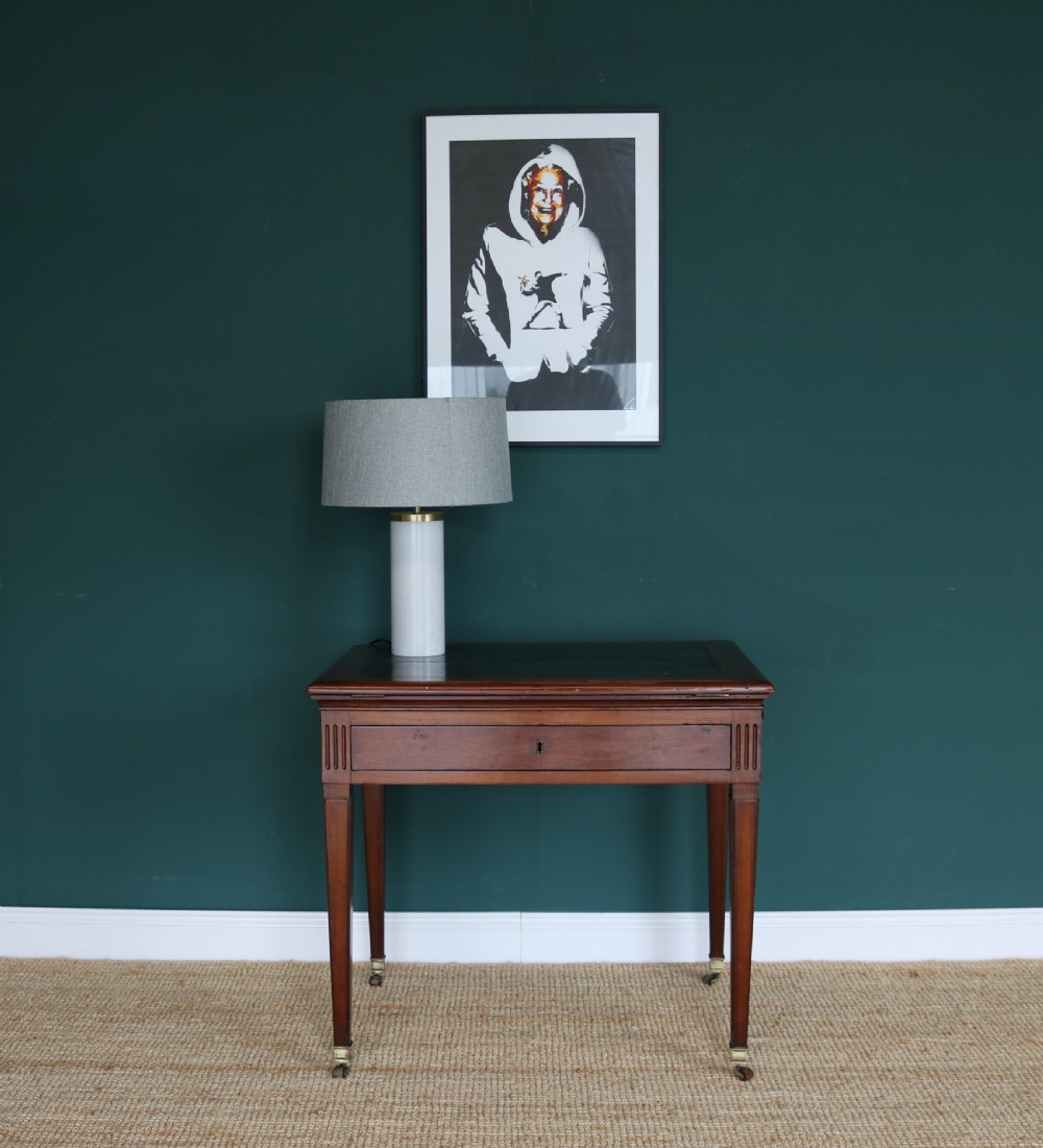 A nineteenth-century French mahogany architects desk featuring a leather inset top, single apron drawer, fluted corners, and tapered legs on brass castors. View VII