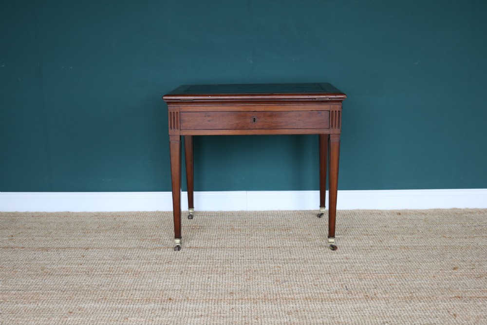 A nineteenth-century French mahogany architects desk featuring a leather inset top, single apron drawer, fluted corners, and tapered legs on brass castors. View IX