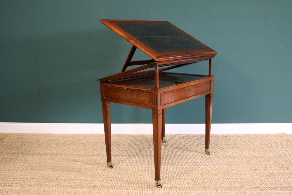 A nineteenth-century French mahogany architects desk featuring a leather inset top, single apron drawer, fluted corners, and tapered legs on brass castors. View X