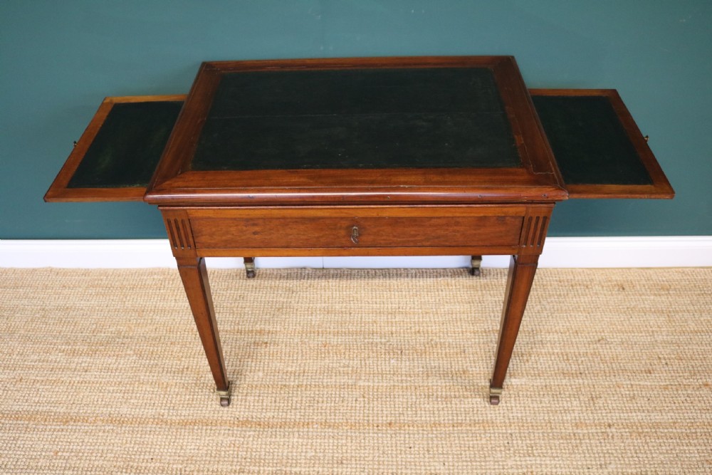 A nineteenth-century French mahogany architects desk featuring a leather inset top, single apron drawer, fluted corners, and tapered legs on brass castors. View XV