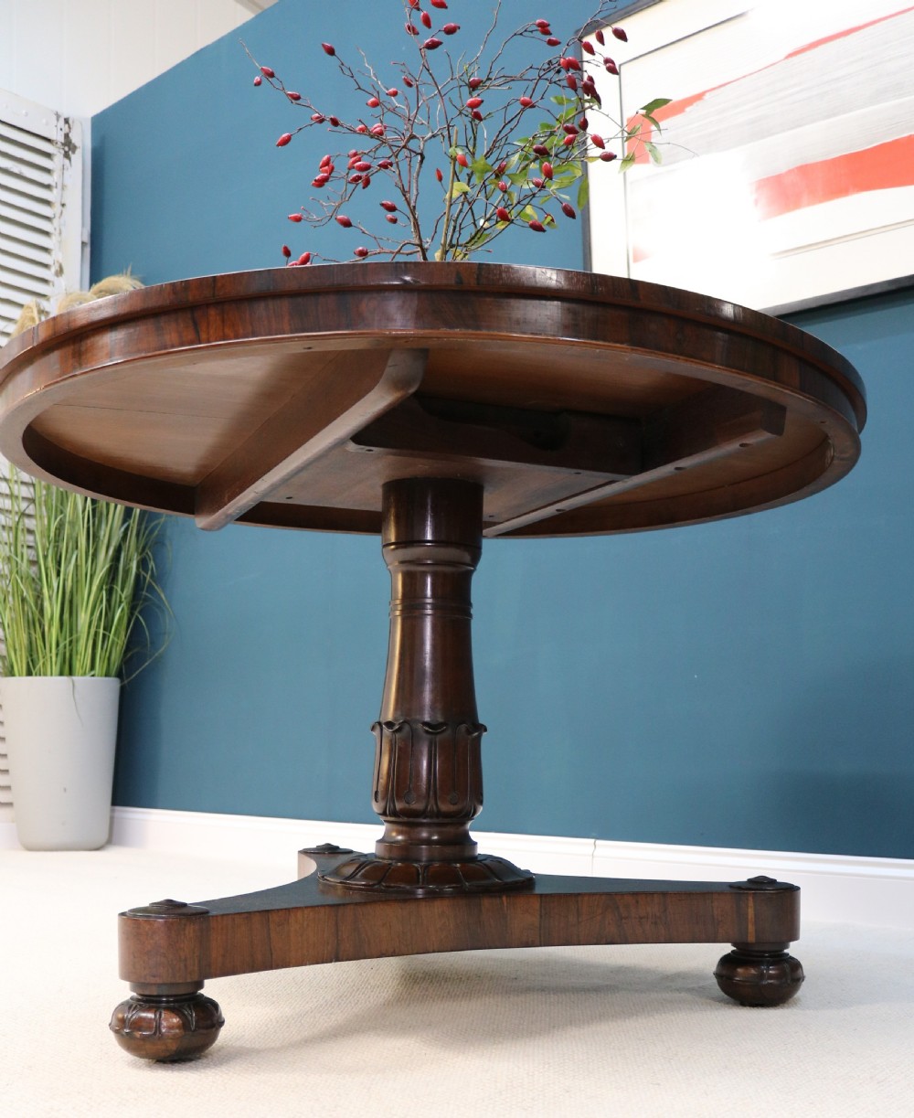 A circular 19th-century William IV rosewood centre table featuring a turned central column on a triform plinth base with carved feet. View XI
