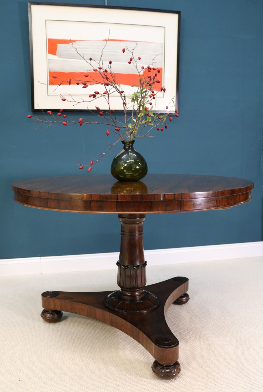 A circular 19th-century William IV rosewood centre table featuring a turned central column on a triform plinth base with carved feet. View XII