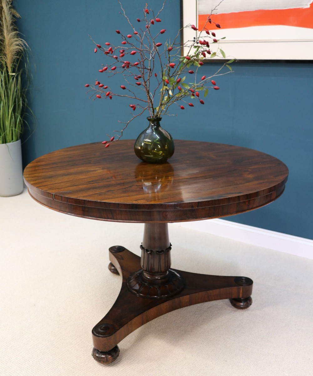 A circular 19th-century William IV rosewood centre table featuring a turned central column on a triform plinth base with carved feet. View XIII