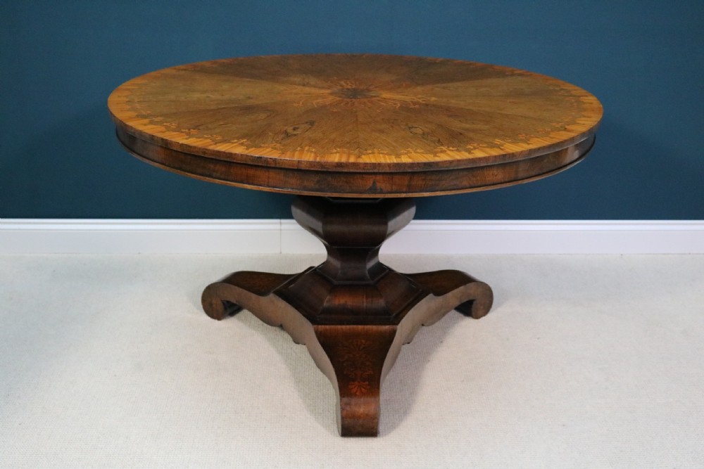 A 19th-century circular walnut centre table featuring floral marquetry inlays, a central faceted pedestal, and a tripartite platform base on scrolled feet. View XV