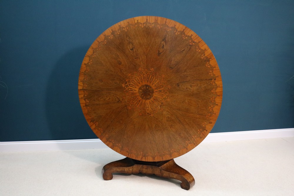 A 19th-century circular walnut centre table featuring floral marquetry inlays, a central faceted pedestal, and a tripartite platform base on scrolled feet. View VIII