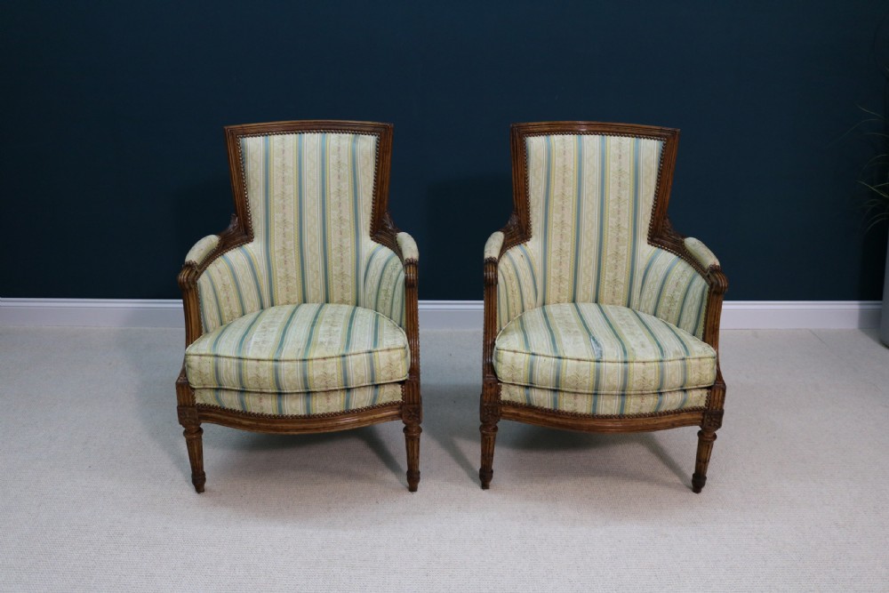 A pair of walnut fauteuil armchairs in French Louis XVI taste