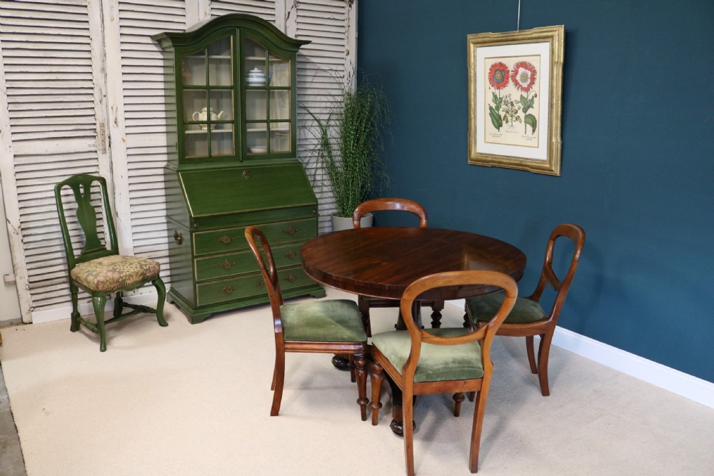A green painted secretaire writing cabinet featuring an arched glazed upper display section, a fall-front desk revealing fitted compartments, three lower drawers with brass handles, and a matching upholstered chair. View III