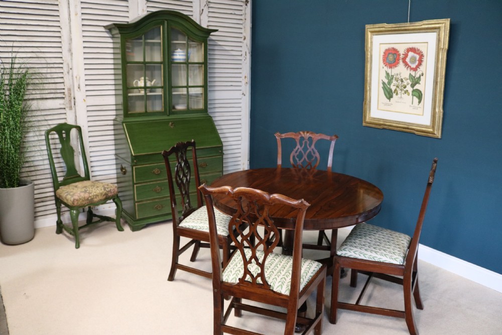 A green painted secretaire writing cabinet featuring an arched glazed upper display section, a fall-front desk revealing fitted compartments, three lower drawers with brass handles, and a matching upholstered chair. View VI