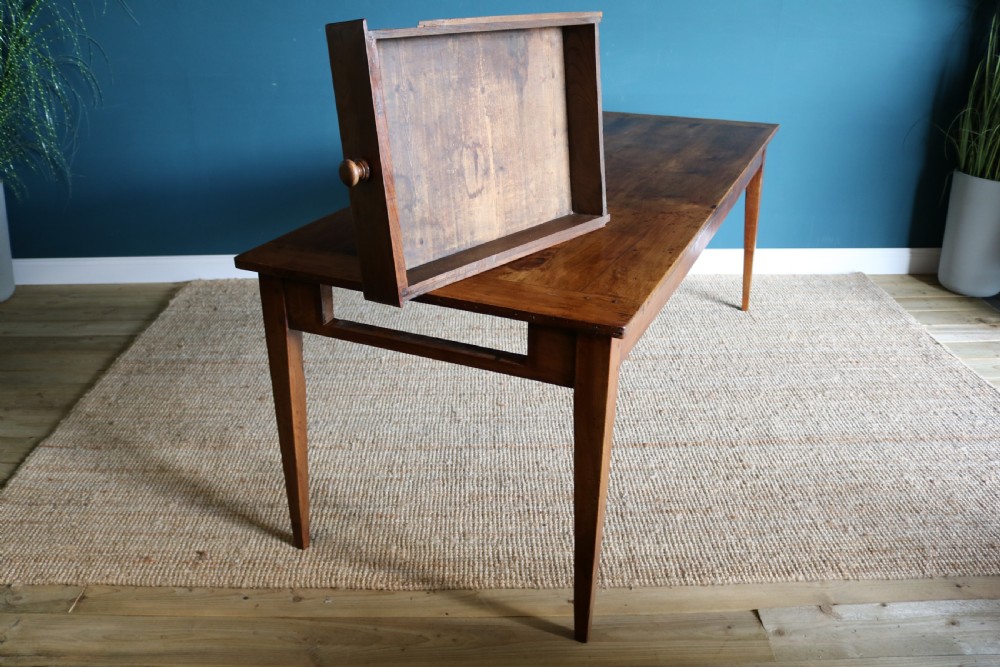 A nineteenth-century French farmhouse table constructed from warm brown cherry wood with tapered square legs and a rectangular plank top. View III