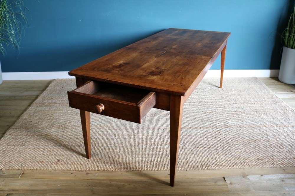 A nineteenth-century French farmhouse table constructed from warm brown cherry wood with tapered square legs and a rectangular plank top. View IV